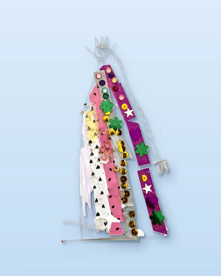 The queen alone, cut out round her own outline: her pencil crown, the taped and sequinned dress, her hands and the lilac pencil shading beside her skirt. The page, the spiral binding and the stickers that were stuck round her are gone. A thin line of the page's foot is left under her hem.