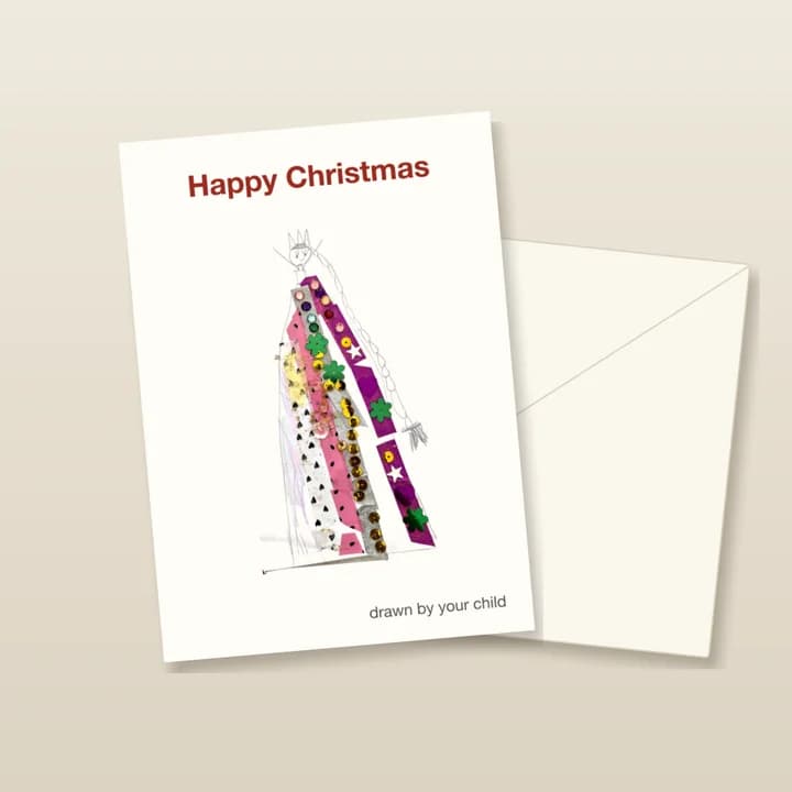 A mockup of the Christmas card, a portrait card standing on its envelope: "Happy Christmas" above a child's drawing of a queen in a sequinned dress.